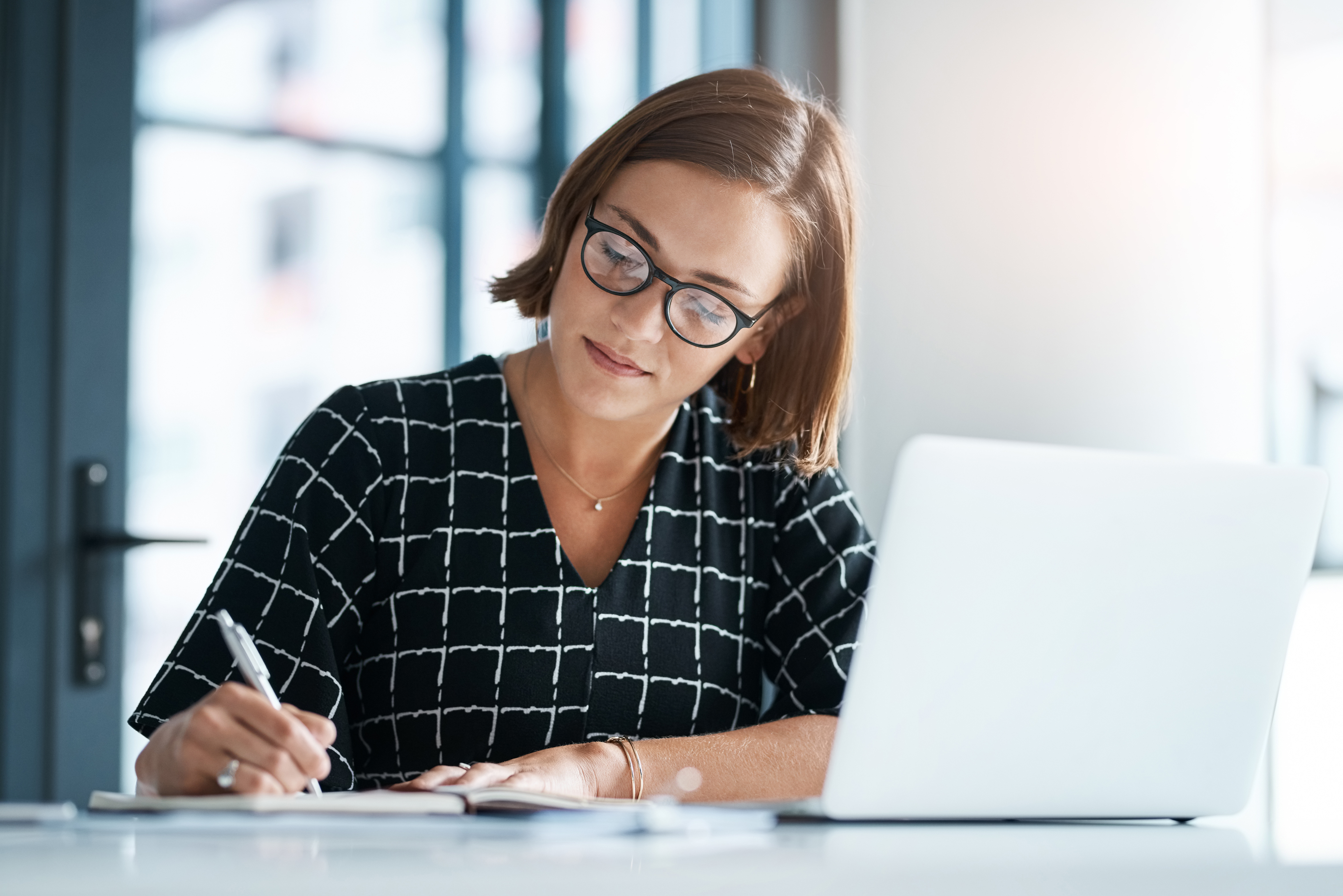 Office, woman and laptop or writing in notebook for proposal, application and requirement to stakeholder. Grant writer, closeup and research funding for non profit organization, submission and review.